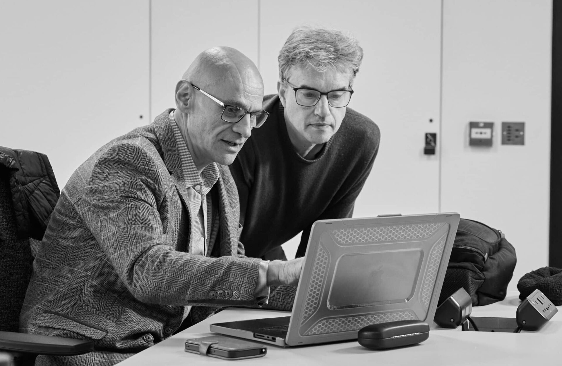 Two men looking at a computer discussing some AI coding.