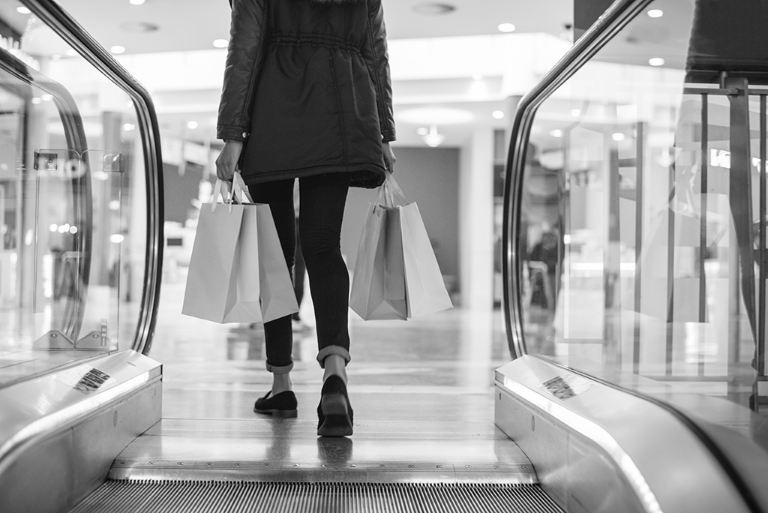 A person walking through a shopping centre carrying shopping bags.